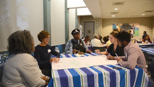 Adults gathering at a table for a "Community Cafe" discussion