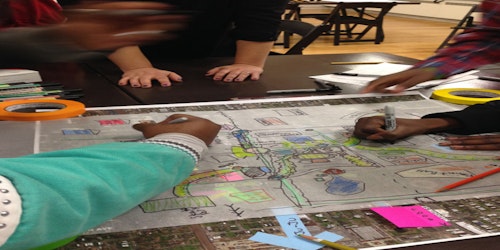 Three kids drawing on paper mapping out spaces in their neighborhood