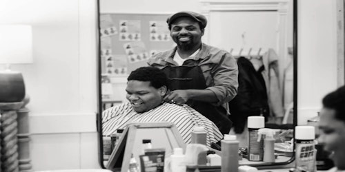 man sitting in chair getting his hair cut