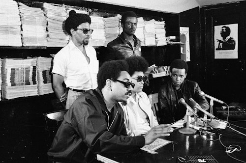 five revolutionaries sitting at a table for a press conference.